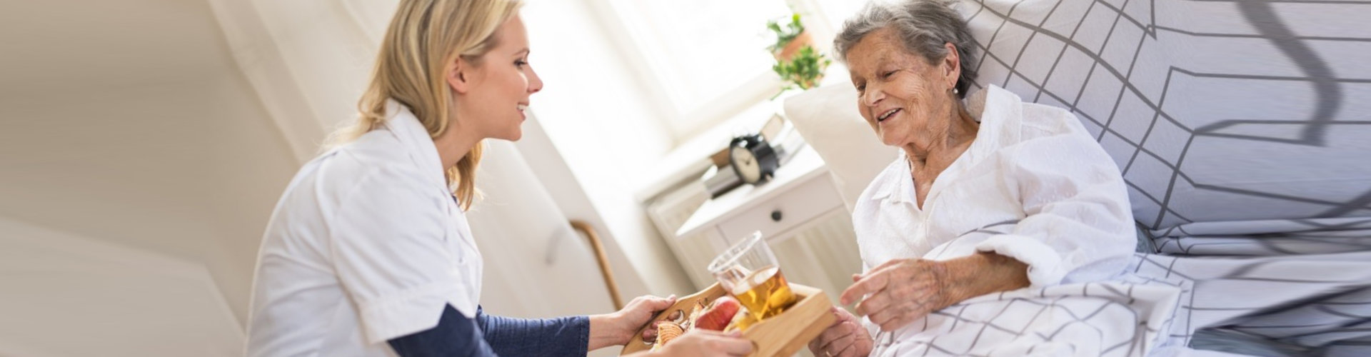 caregiver serving an elderly woman a meal